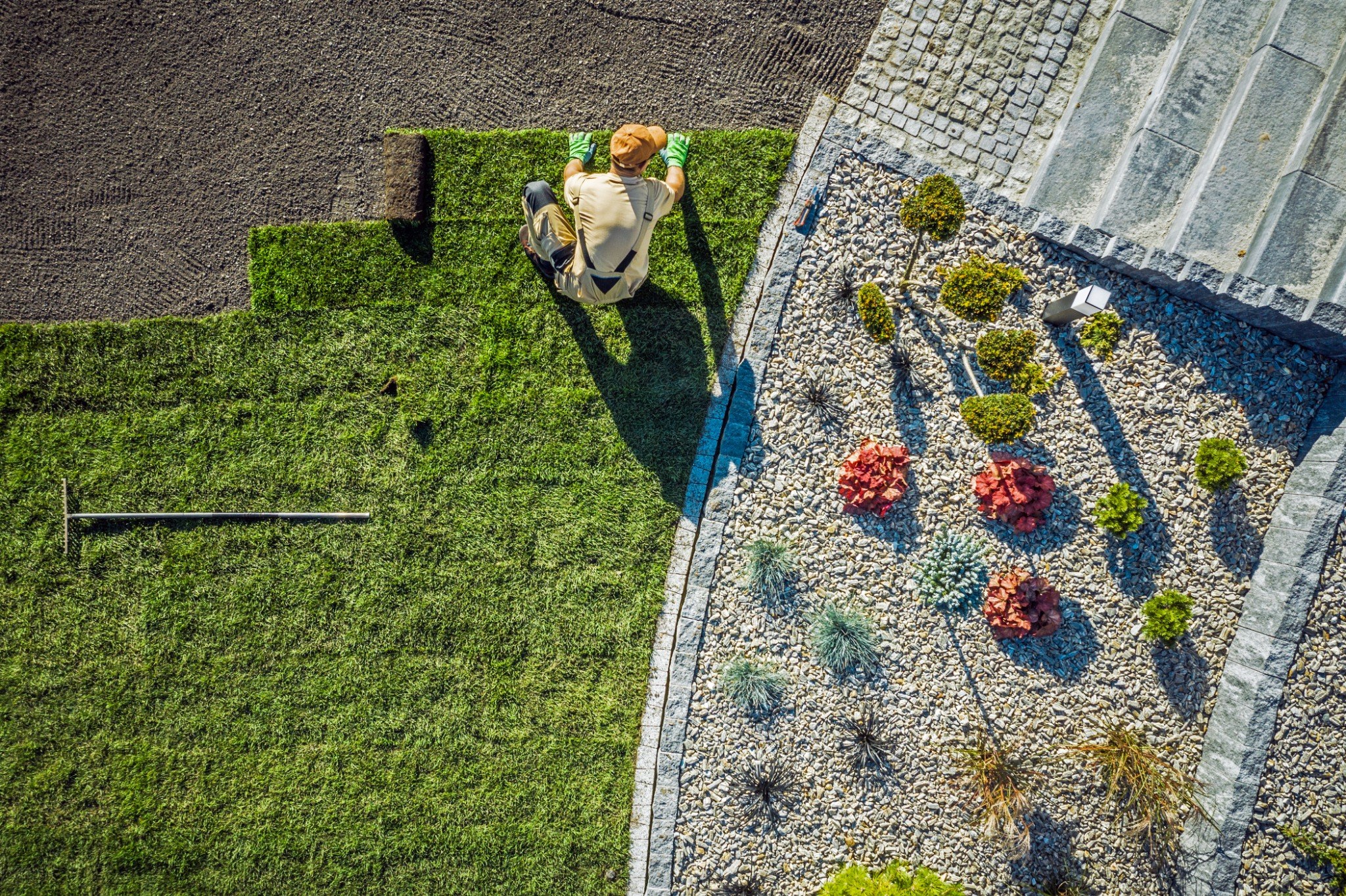 Aerial view of person relaxing on lawn next to landscaped garden with gravel and plants